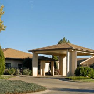A single-story building with a covered entrance and surrounding landscaping under a clear blue sky.
