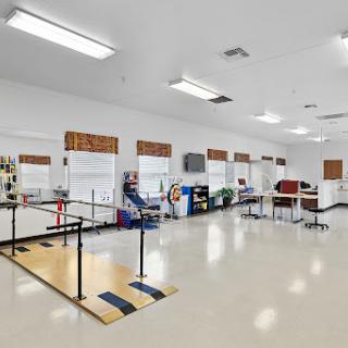 A spacious and modern rehabilitation center for physical therapy, featuring various exercise equipment and an open layout.