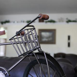 A close-up view of a bicycle with a stylish basket and wooden handlebars, set against a cozy interior.