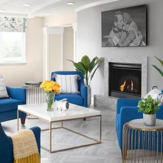 Modern living room with blue chairs and a cozy fireplace.
