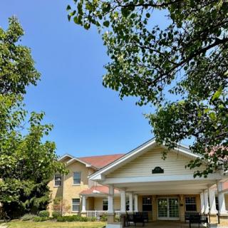 A sunny day showcasing a charming residential building framed by lush greenery.