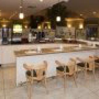 A modern cafe interior with a long counter and wooden chairs.