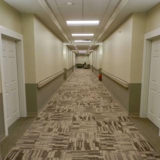 A long corridor with multiple doors and patterned carpet flooring.