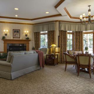 A cozy living room and dining area with traditional decor, featuring a fireplace, comfortable sofa, and elegant chandelier.