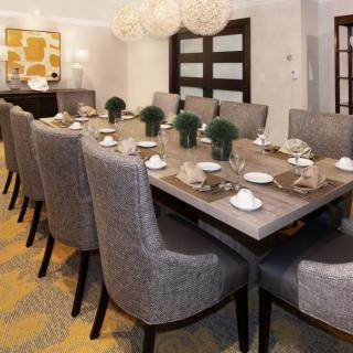 A modern dining room with a large table set for a meal, featuring elegant gray chairs and tasteful decor.