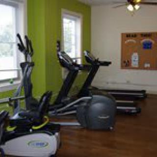 A small gym with treadmills and an elliptical machine in a bright, well-lit room.