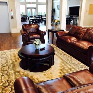A cozy living room with leather sofas, a round coffee table, and a patterned carpet on a wooden floor.