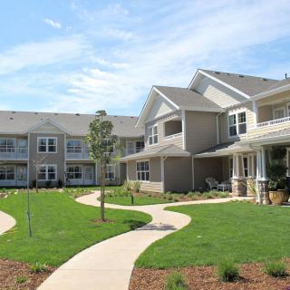 A modern residential apartment complex with a well-maintained lawn and winding pathways.