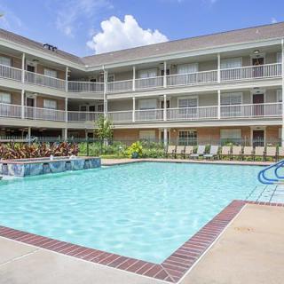 An outdoor swimming pool surrounded by a multi-story hotel with balconies.