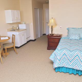 A cozy studio apartment featuring a bed, kitchenette, and dining area.
