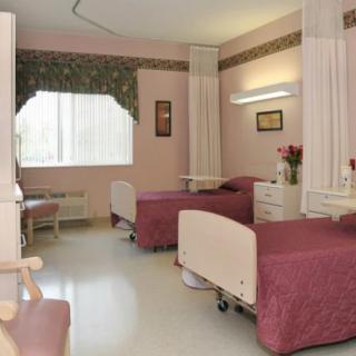 A clean, well-lit hospital room with two beds and privacy curtains.
