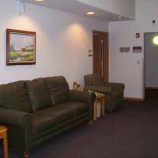 A cozy lobby area with a sofa, armchair, and wall painting.