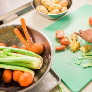 A person preparing vegetables on a cutting board in the kitchen.
