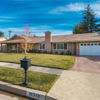 A suburban house with a well-maintained lawn and a driveway leading to a garage.