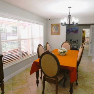 A well-lit dining room with an orange tablecloth, elegant chairs, and a chandelier.