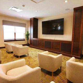 A cozy lounge area with white chairs and a large TV.