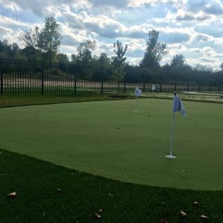 A peaceful view of a golf putting green under a cloudy sky.
