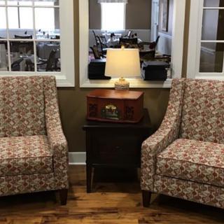 Two patterned chairs flank a small table with a lamp in a cozy living room setting.