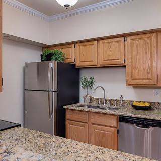 A modern kitchen with wooden cabinets, stainless steel appliances, and a granite countertop.