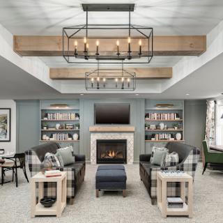 A cozy and modern living room featuring stylish furniture, a warm fireplace, and ample shelving for books.