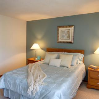 A cozy bedroom with a neatly made bed, two nightstands, and soft lighting.