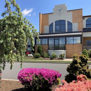 A vibrant garden in front of a modern building against a clear blue sky.
