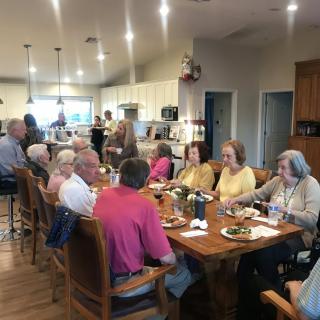 A group of people enjoying a meal together in a kitchen setting.
