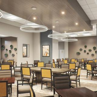 A modern dining area with multiple tables and chairs, featuring contemporary lighting fixtures.