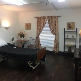 A well-furnished hospital room featuring a patient bed, decorative curtains, and various furniture elements.