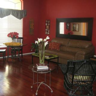A cozy living room featuring warm red walls and stylish furniture, perfect for relaxation.