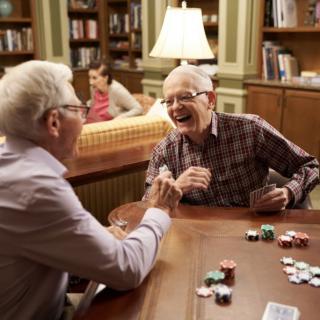 Two seniors enjoying a lively game of poker in a library setting.