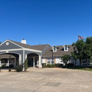 A large residential-style building with a covered entrance, set against a clear blue sky.