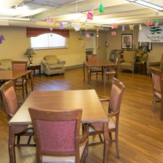 A well-lit community room with tables and chairs arranged for social gatherings.