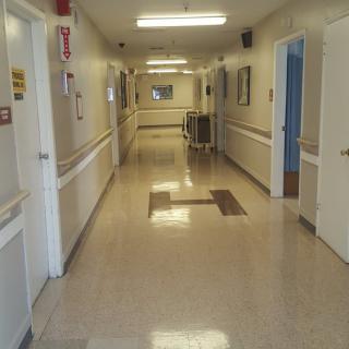 An empty hospital corridor with polished floors and bright lighting.