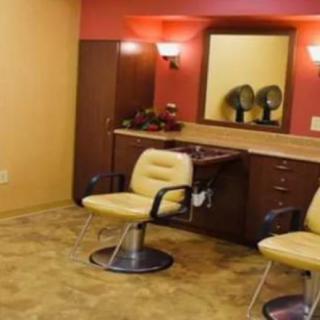 A salon interior with chairs, mirrors, and hair dryers on the counter.
