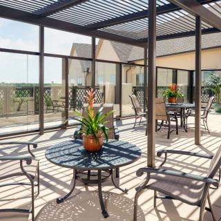 A modern patio with a pergola, featuring outdoor seating and plants.