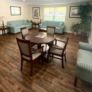 A cozy living room with a wooden floor, featuring sofas and a dining table with chairs.