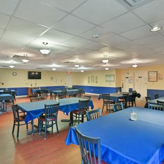 A spacious dining area with blue tablecloths and neatly arranged tables and chairs.