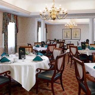 An elegant dining room with formal table settings and chandeliers.