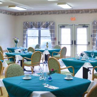 A spacious dining area with neatly set tables featuring blue tablecloths, ready for guests.