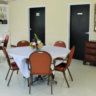 A small meeting room with a table set up and chairs around it, featuring a floral centerpiece.