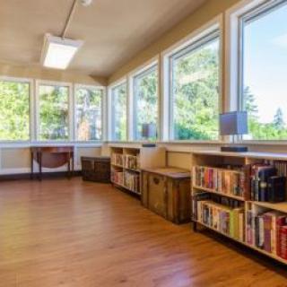 Bright and inviting reading room with bookshelves lining large windows.