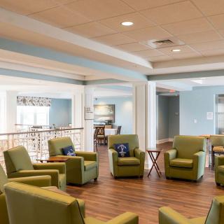 A spacious and comfortable seating area with green chairs and ample natural light.