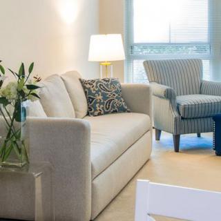 A cozy living room with a sofa, armchair, and table lamp creating a warm atmosphere.