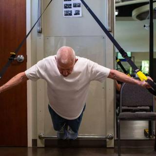An individual performing a suspended push-up using TRX straps in a gym setting.