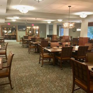 A spacious and warmly lit dining area featuring wooden furniture and an inviting atmosphere.