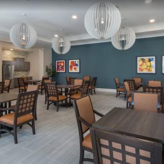 A modern dining area with neatly arranged tables and chairs, featuring stylish hanging lights and colorful artwork on the walls.