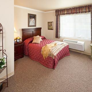 A cozy bedroom with a neatly made bed and large window.