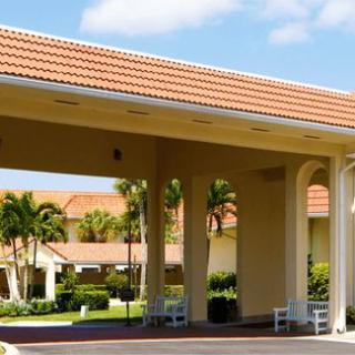A building entrance with a tiled roof and palm trees, on a sunny day.