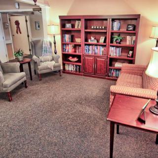 A cozy office space with a bookshelf, chairs, and a desk.